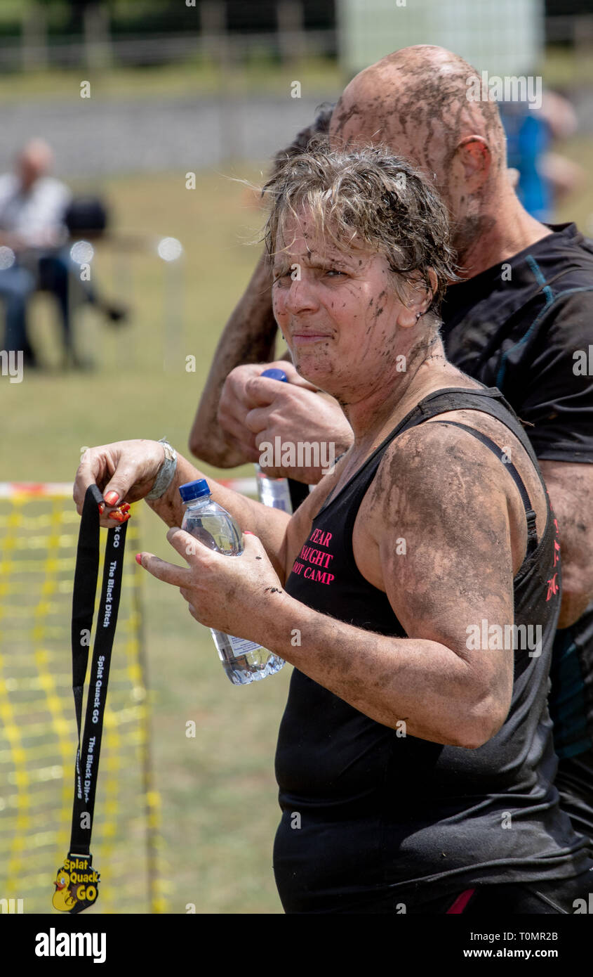 La boue femme runner détient sa médaille à l'arrivée Banque D'Images
