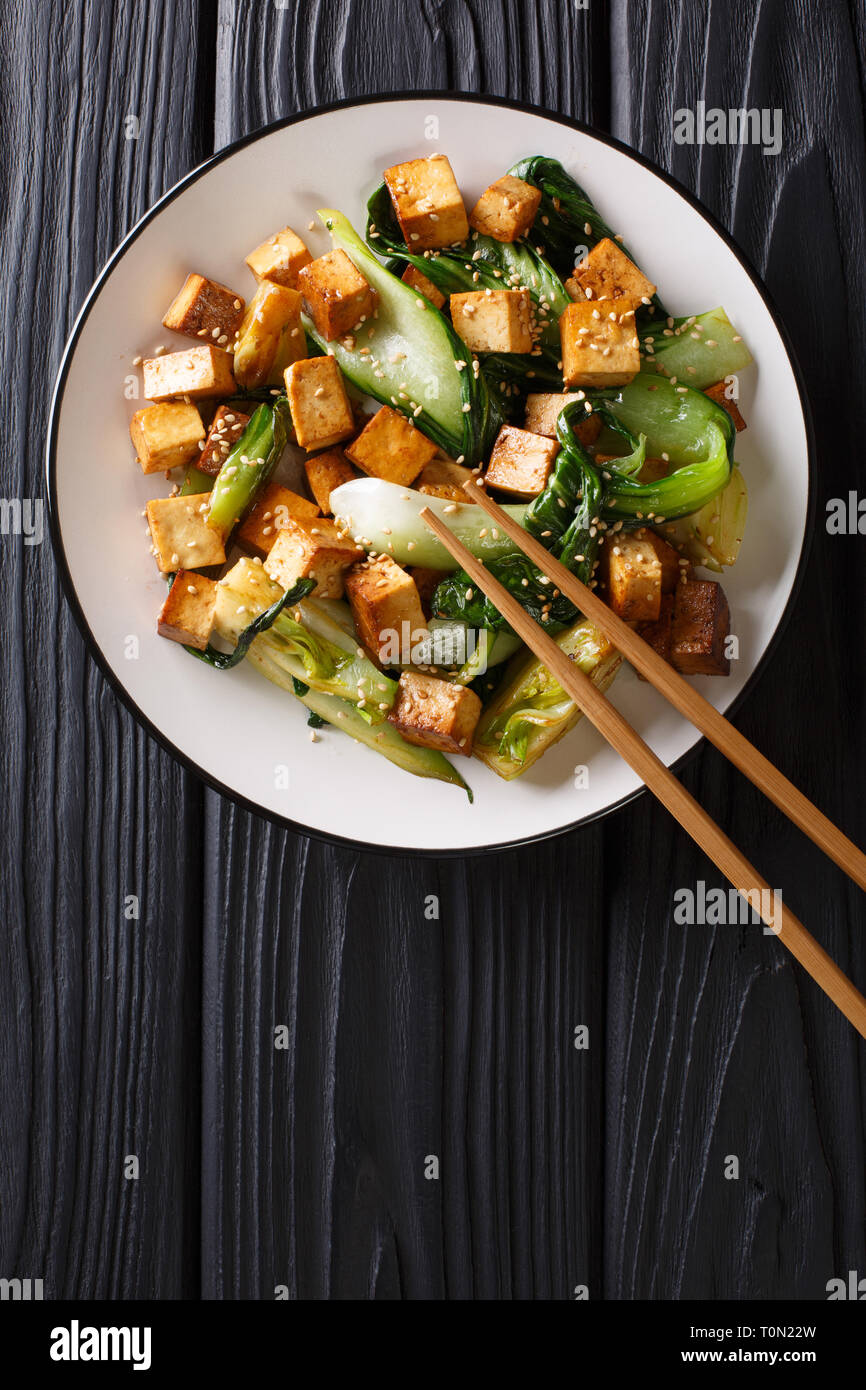 Tofu sauté avec bok choy et les graines de sésame sur une assiette sur la table. Haut Vertical Vue de dessus Banque D'Images