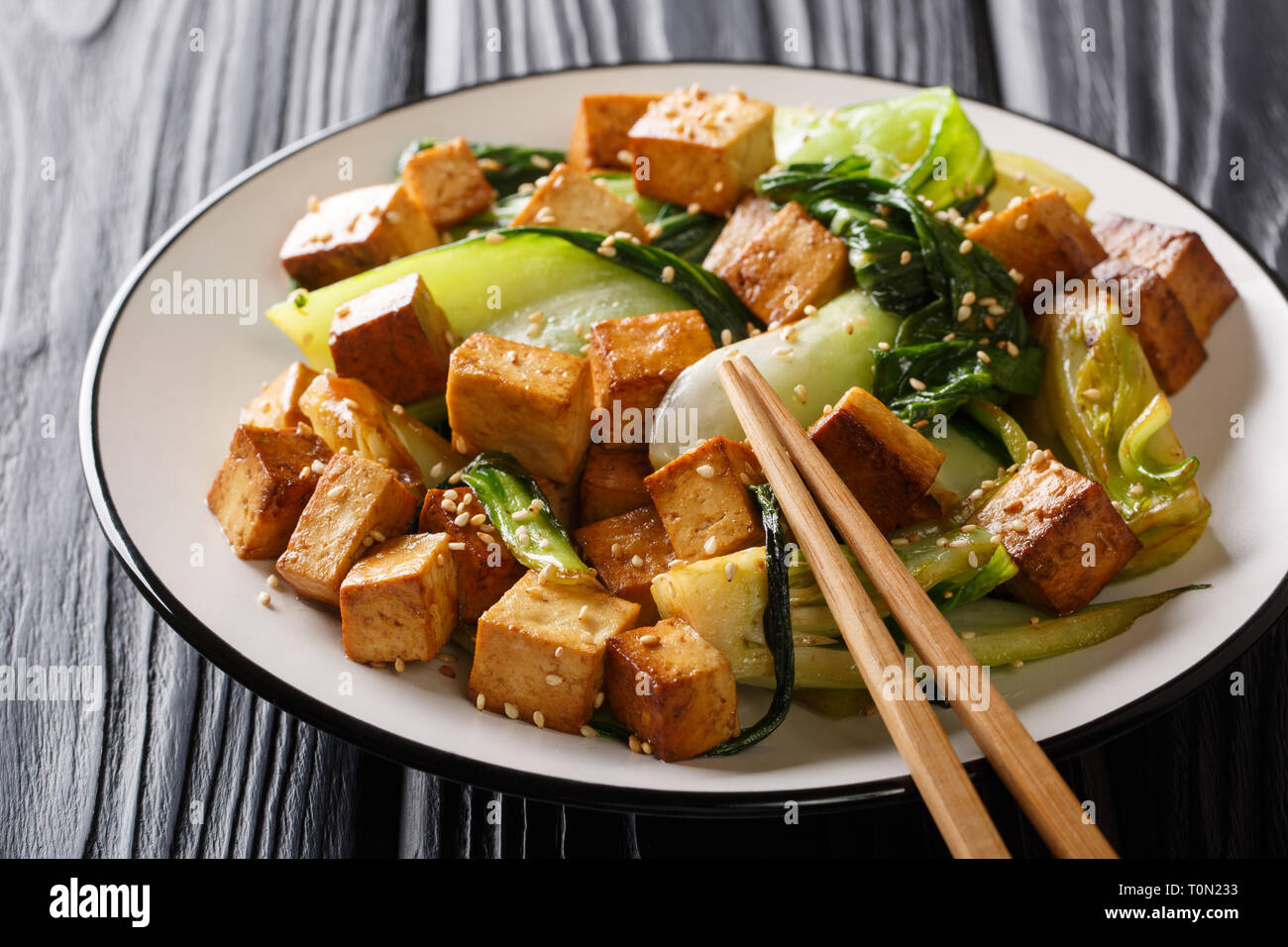 Tofu frit traditionnel avec bok choy, de la sauce soja et sésame close-up sur une plaque sur la table horizontale. Banque D'Images