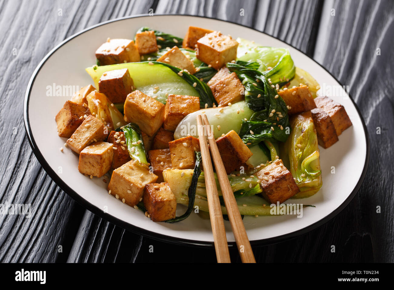 Veggie tofu frit avec petits bok choy, la sauce soja et les graines de sésame gros plan sur une assiette sur la table horizontale. Banque D'Images