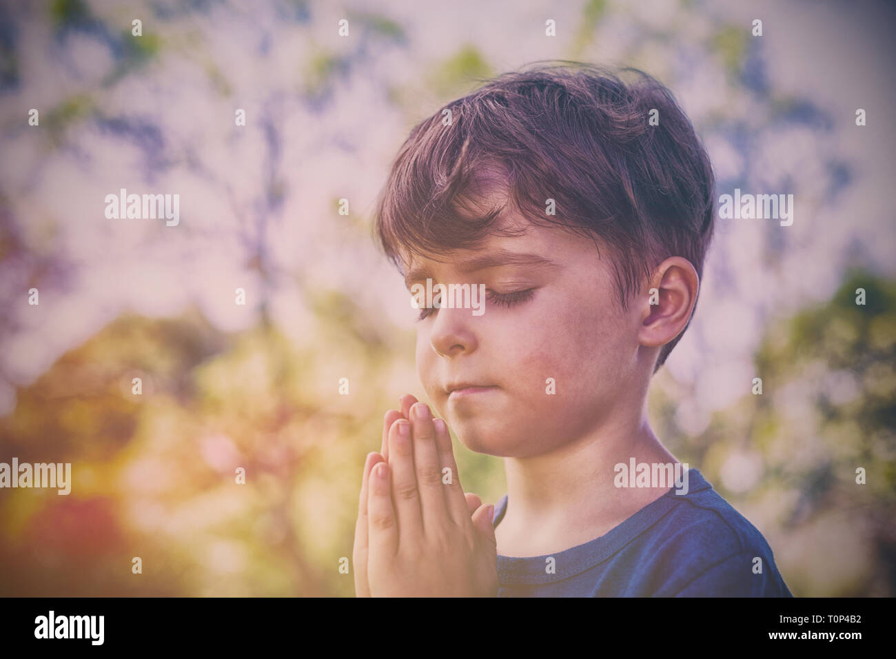 Garçon en prière avec les yeux fermés Banque D'Images