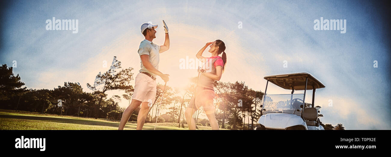 Toute la longueur du joueur de golf couple giving high five Banque D'Images