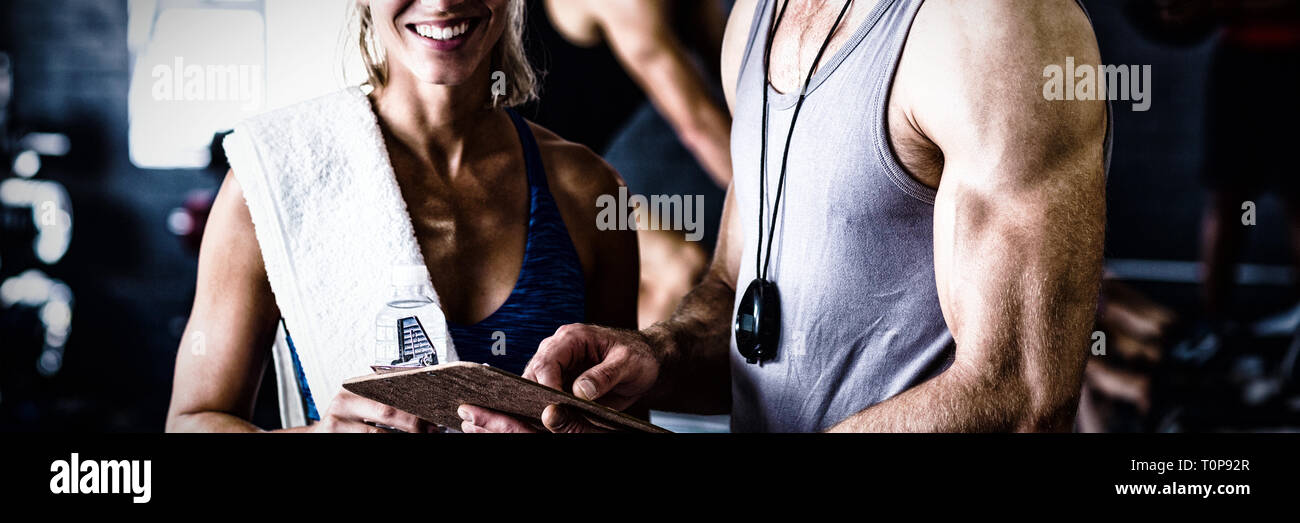 Portrait of smiling instructeur de conditionnement physique avec femme en salle de sport Banque D'Images