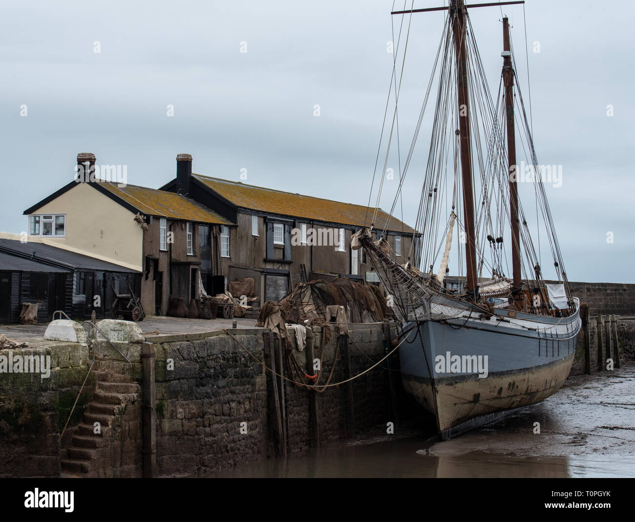 Lyme Regis, dans le Dorset, UK. 21 mars 2019. Navire à voile traditionnelle 1907 'Irene' amarré à Lyme Regis port comme le 100 pied ketch et le Cobb historique bâtiments sont transformés en un décor de cinéma en état de disponibilité pour continué le tournage de Ammonite avec Kate Winslet et Saoirse Ronan. Réalisé par Francis Lee, la fiction dramatique dépeint célèbre chasseur de fossiles que Mary Anning femme gay suscitant des débats entre les historiens et sur les médias sociaux. Le film est prévu d'apporter un coup de pouce pour le tourisme et l'économie locale. Credit : Celia McMahon/Alamy Live News Banque D'Images
