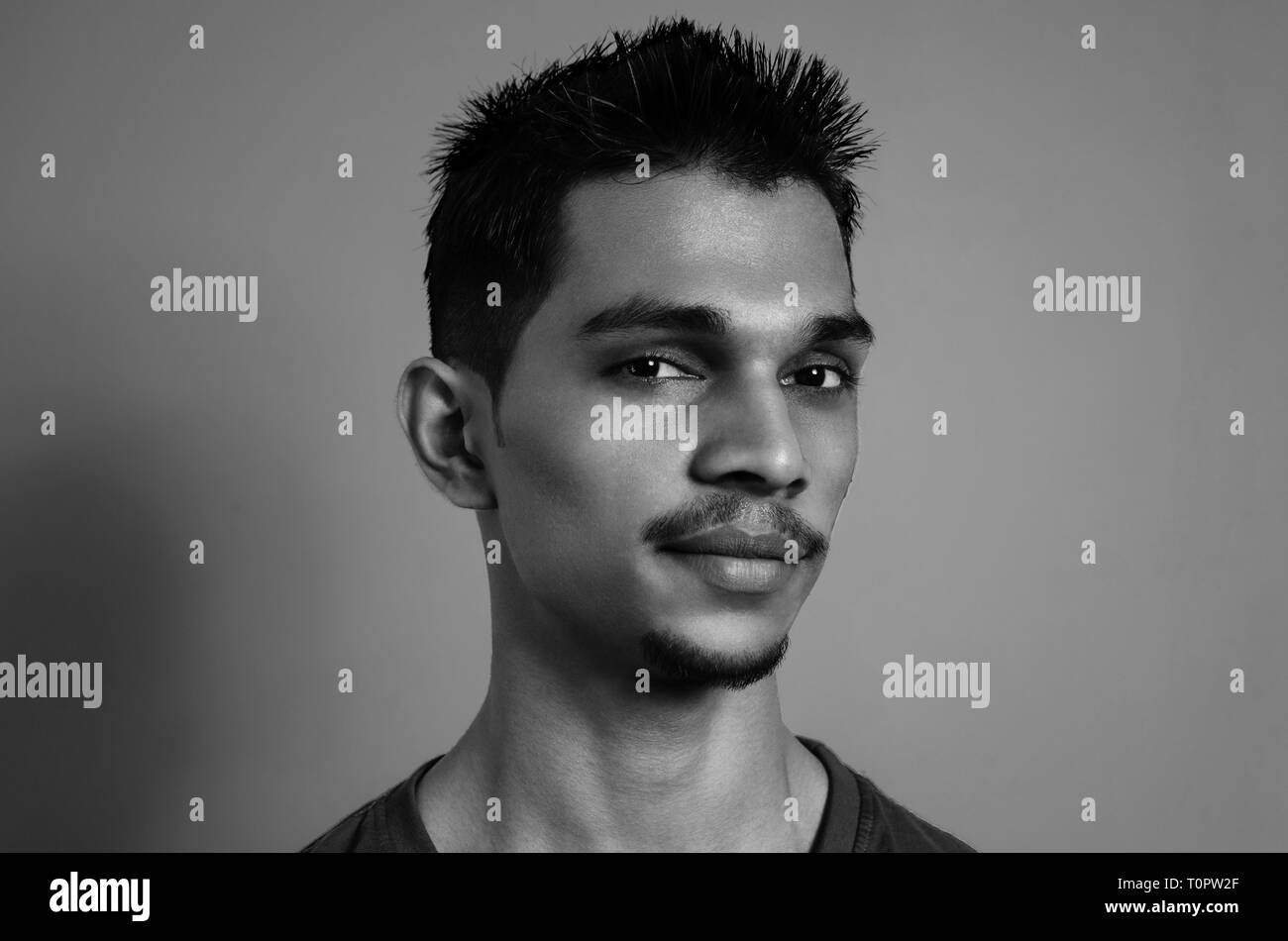 Noir et blanc, portrait, portrait d'un jeune Indien de 22 ans à la recherche en appareil photo sur un fond blanc. Banque D'Images