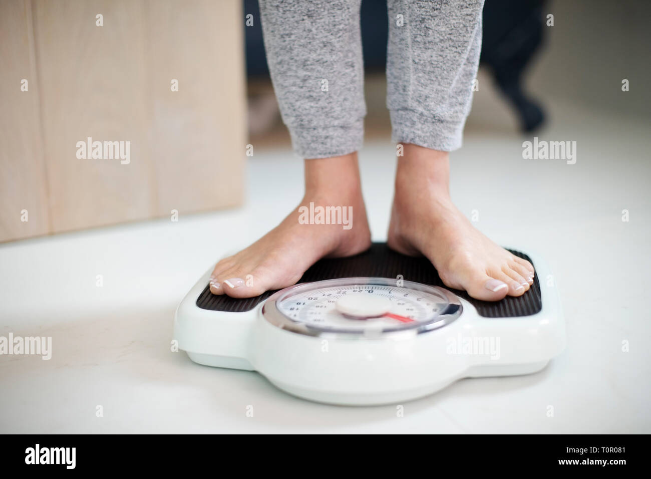 Portrait de femme debout sur un pèse-personne à la maison Banque D'Images