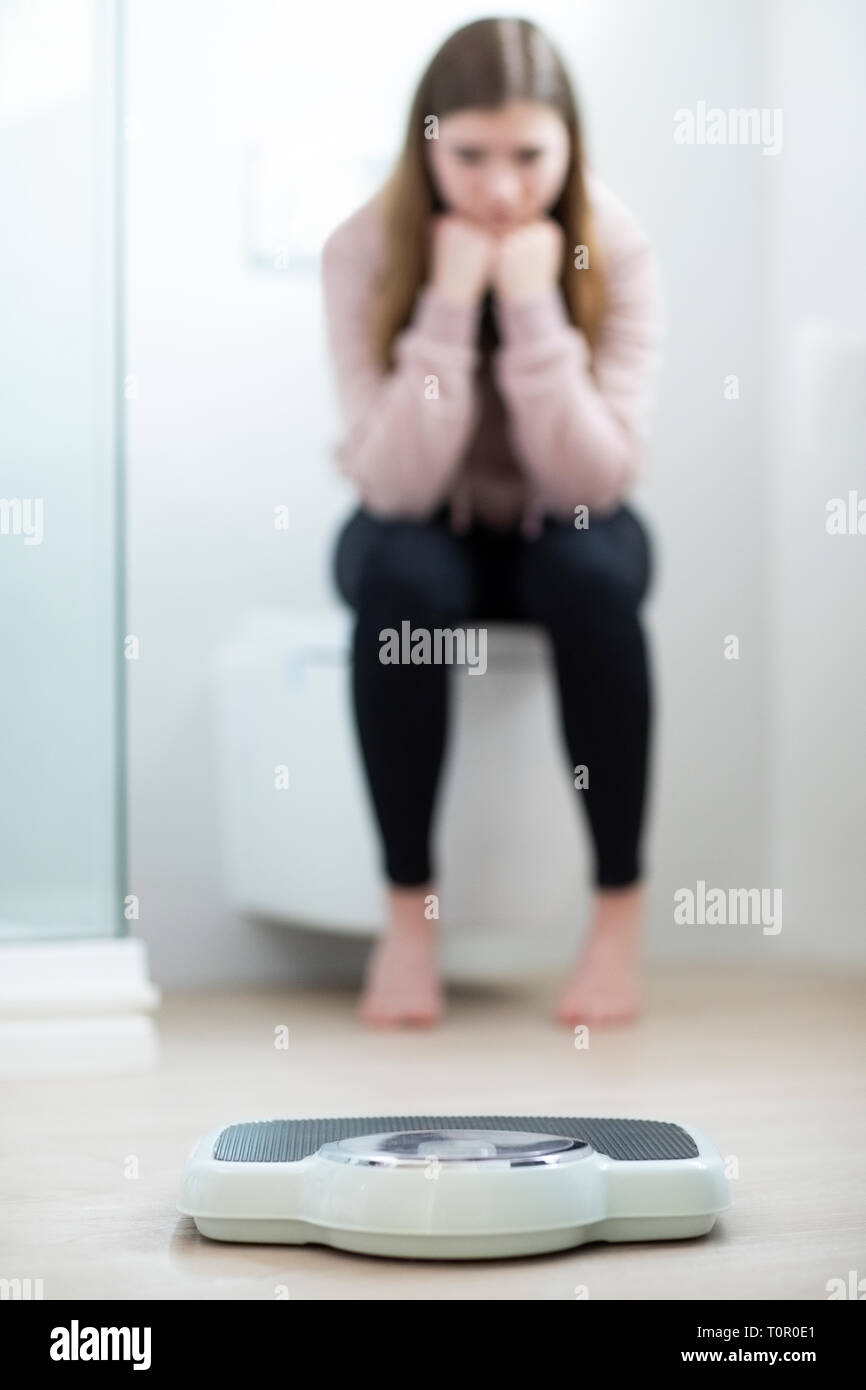 Malheureux Teenage Girl Sitting dans la salle de bains à la recherche à des échelles Banque D'Images