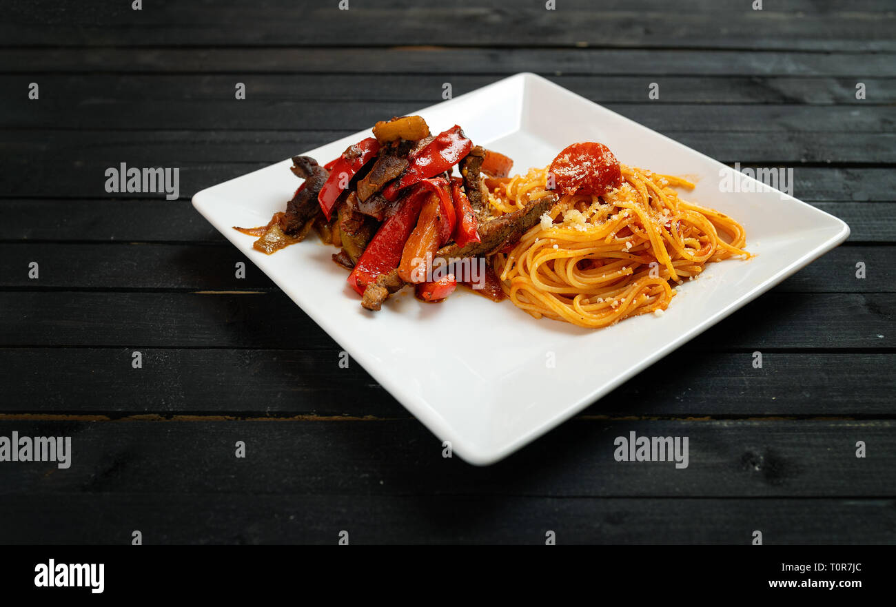 Les pâtes spaghetti fait maison avec de la viande de boeuf et légumes divers sur un tableau noir en bois. L'éclairage discret Banque D'Images