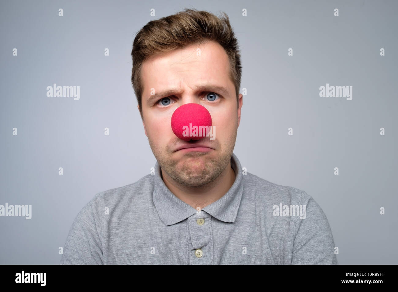 Mature man wearing clown nez rouge isolé sur fond gris Banque D'Images