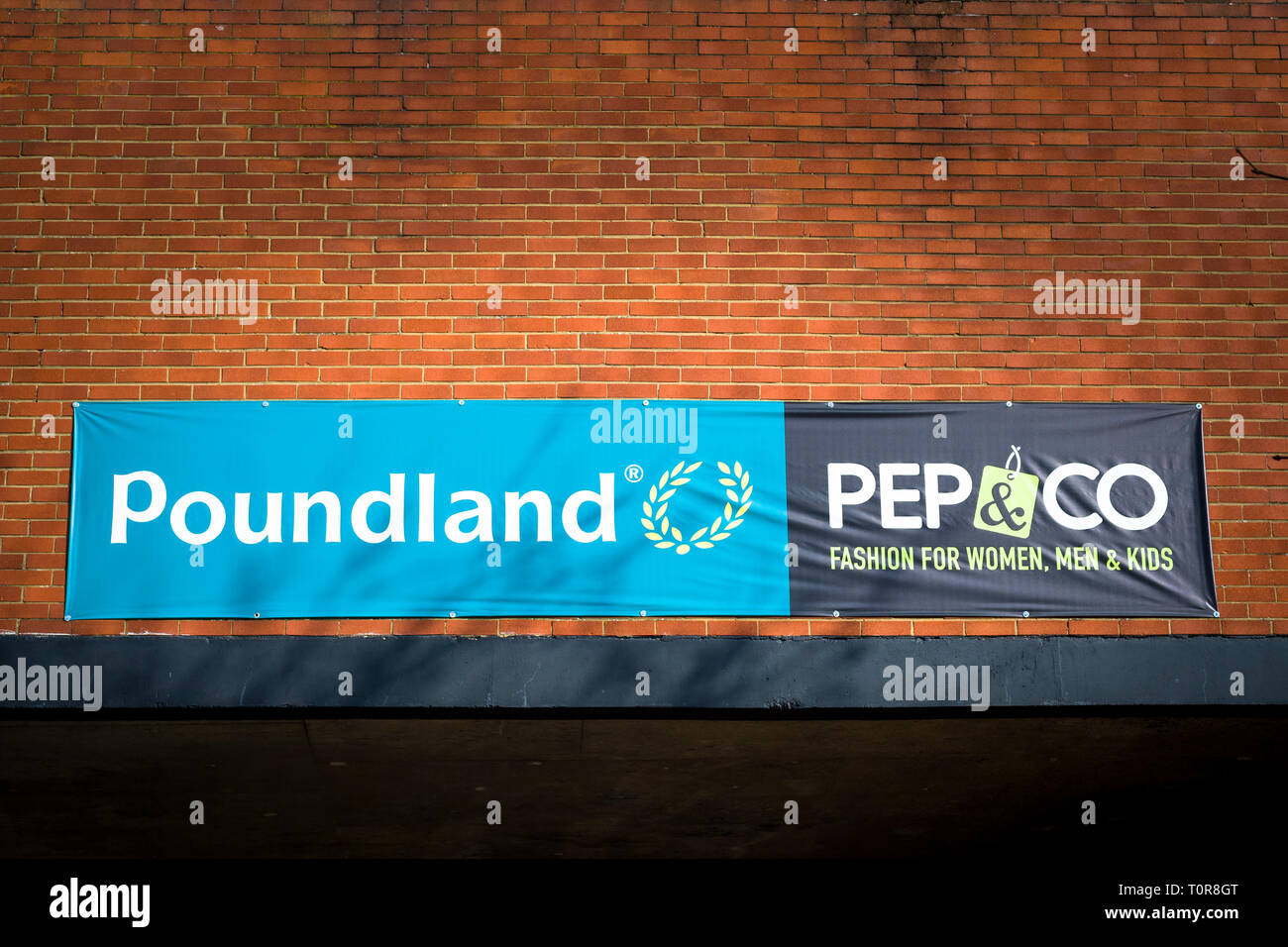 Banner s'étire à travers la paroi arrière d'une unité de vente au détail d'un parking face à l'annonce de nom d'entreprise POUNDLAND et PEP & Co à Devizes Wiltshire, Angleterre Banque D'Images