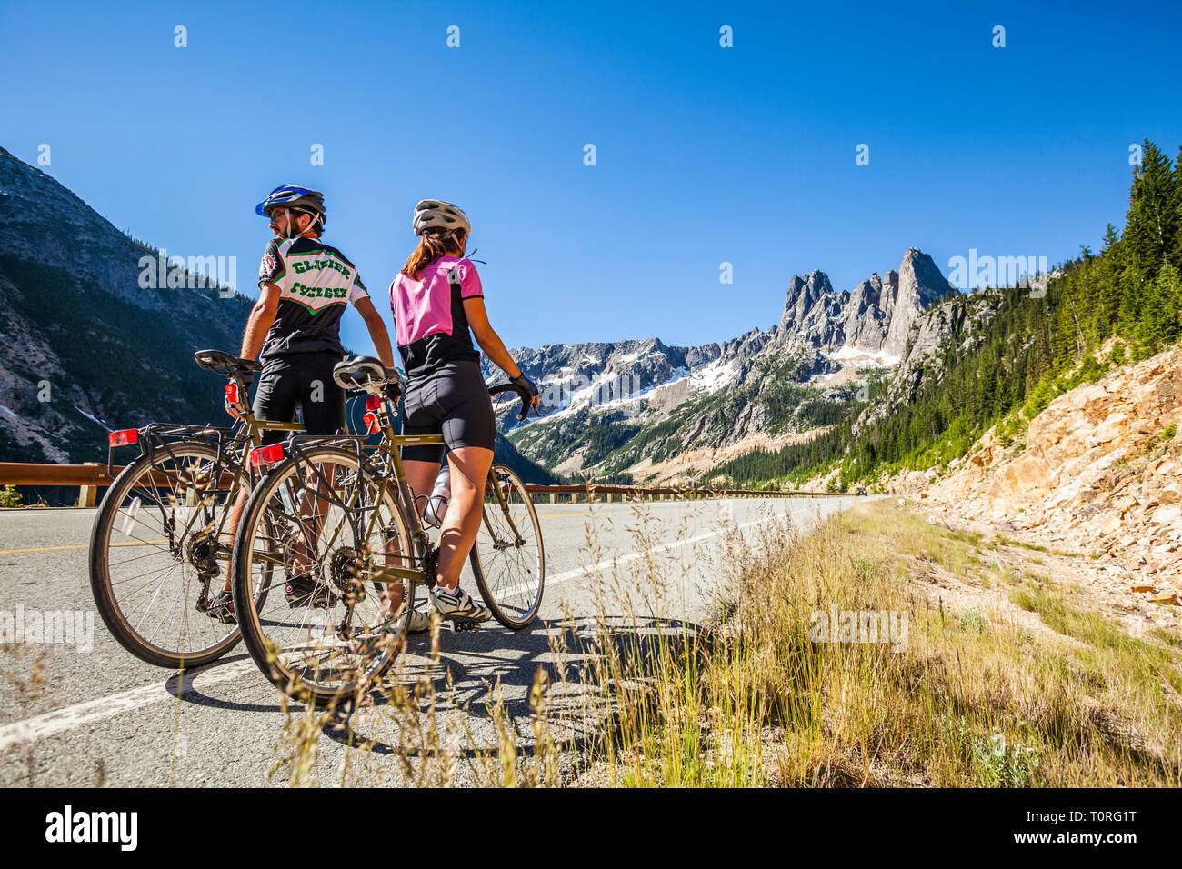 Un jeune couple debout avec leurs bicyclettes en attente d'autres cavaliers. Col de Washington dans le Nord des cascades de l'État de Washington, USA. Banque D'Images