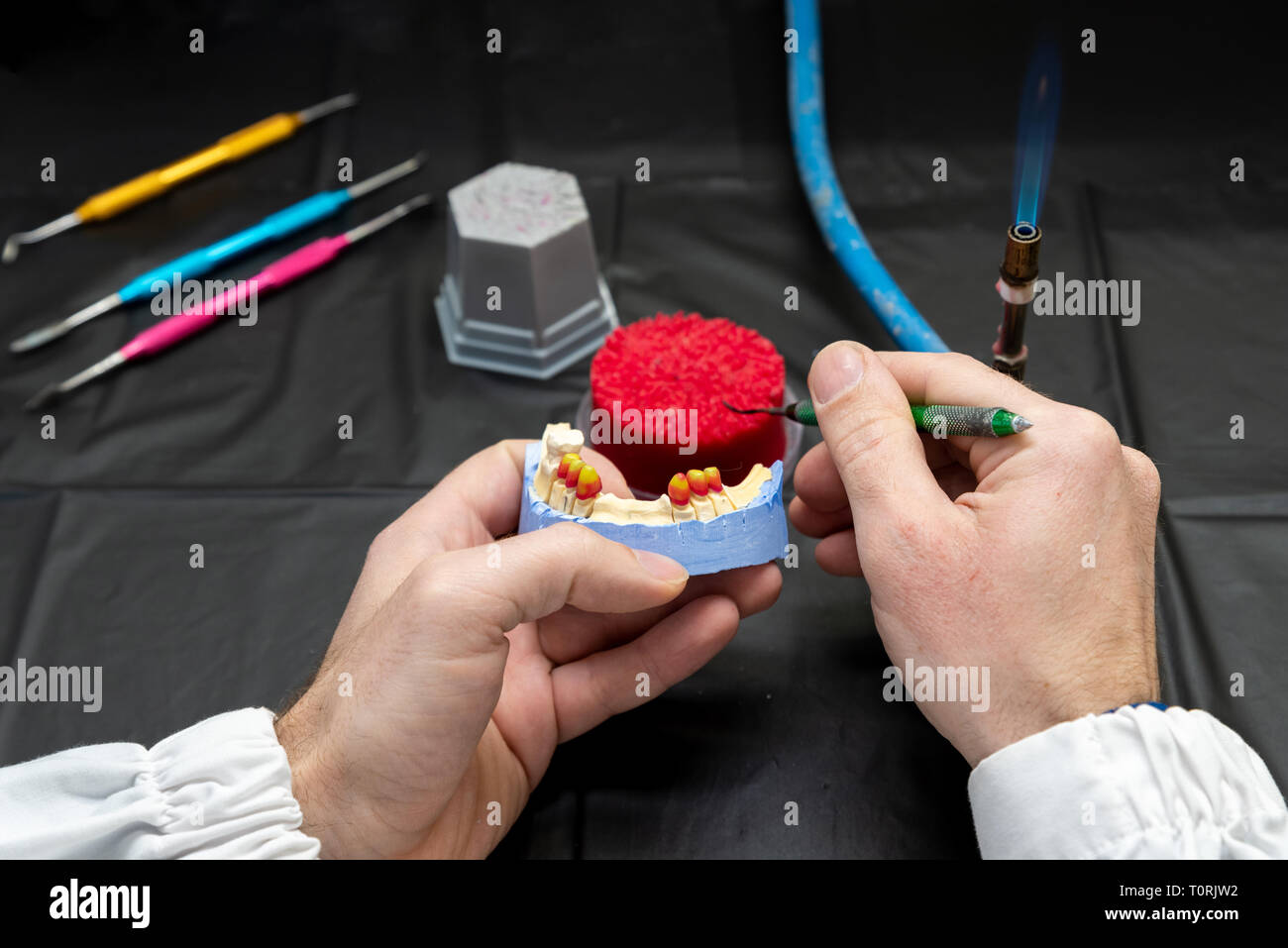 Technicien dentaire ou un dentiste avec un homme travaillant dans un laboratoire de prothèses avec de la cire sur un modèle de la mâchoire Banque D'Images