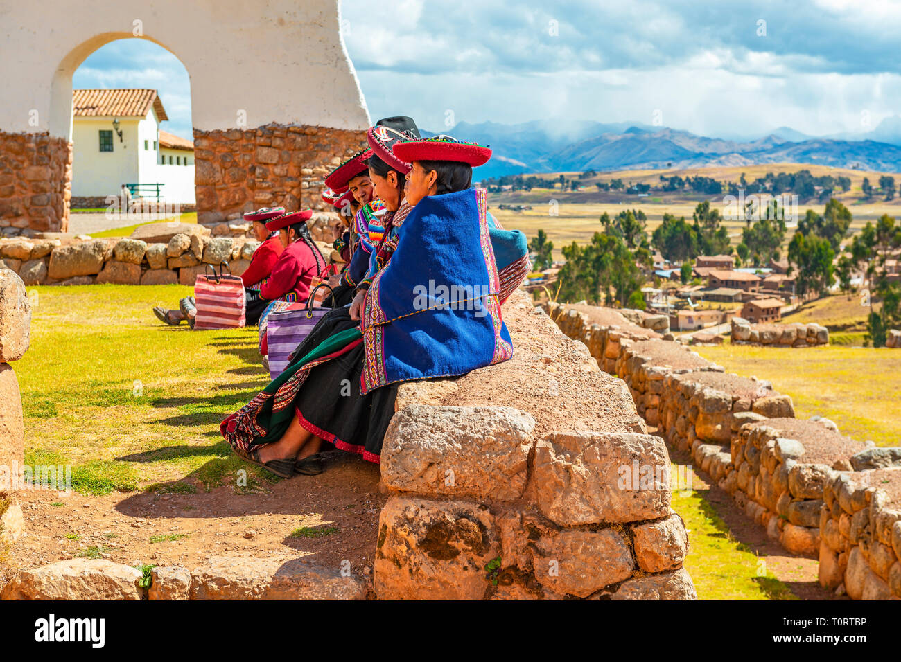 Un groupe de femmes autochtones Quechua péruvien assis sur un ancien mur Inca dans la ruine Inca archéologique de Chinchero, province de Cusco, Pérou. Banque D'Images