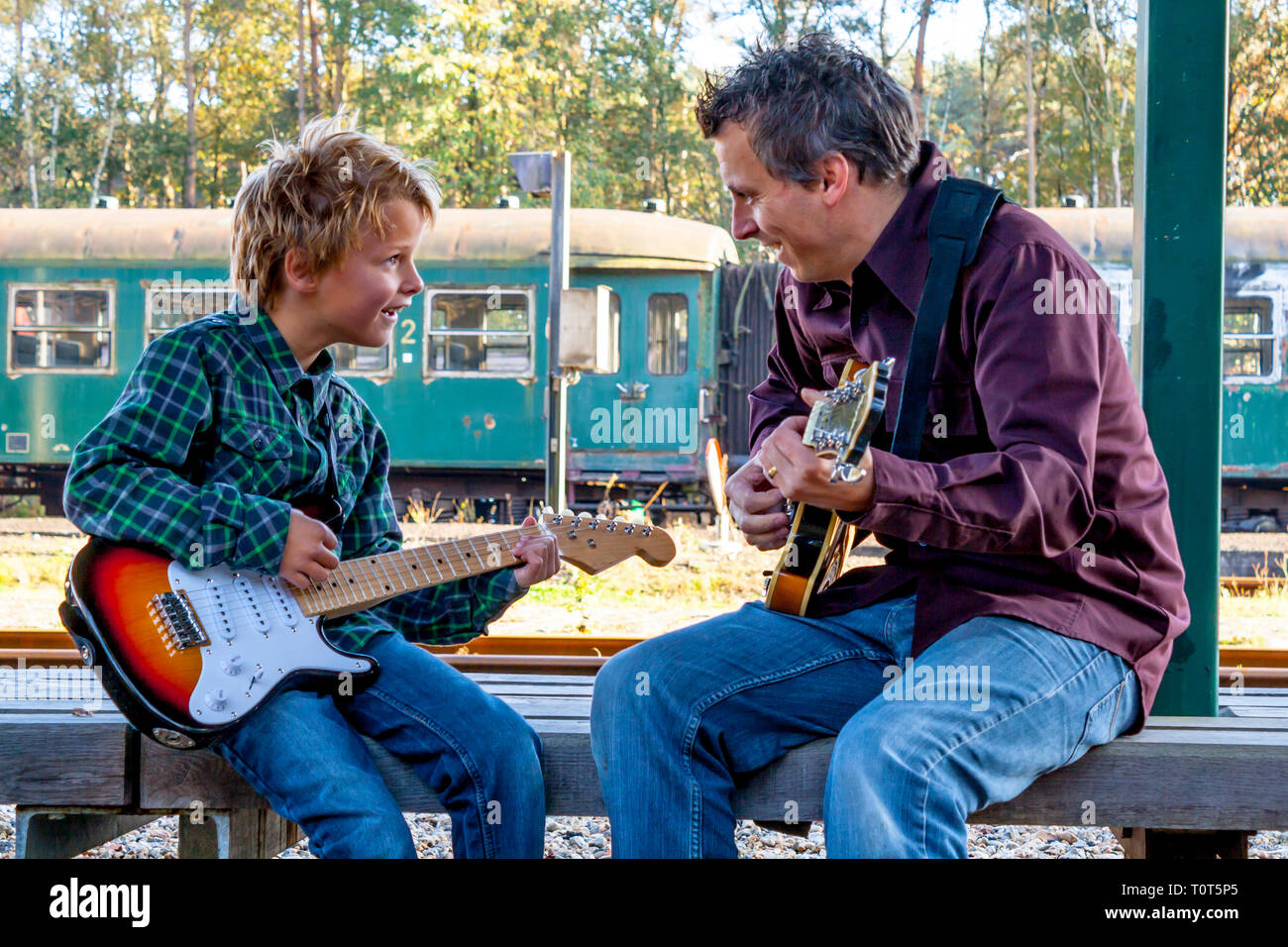Garçon et papa qui joue de la guitare en attendant le train Banque D'Images