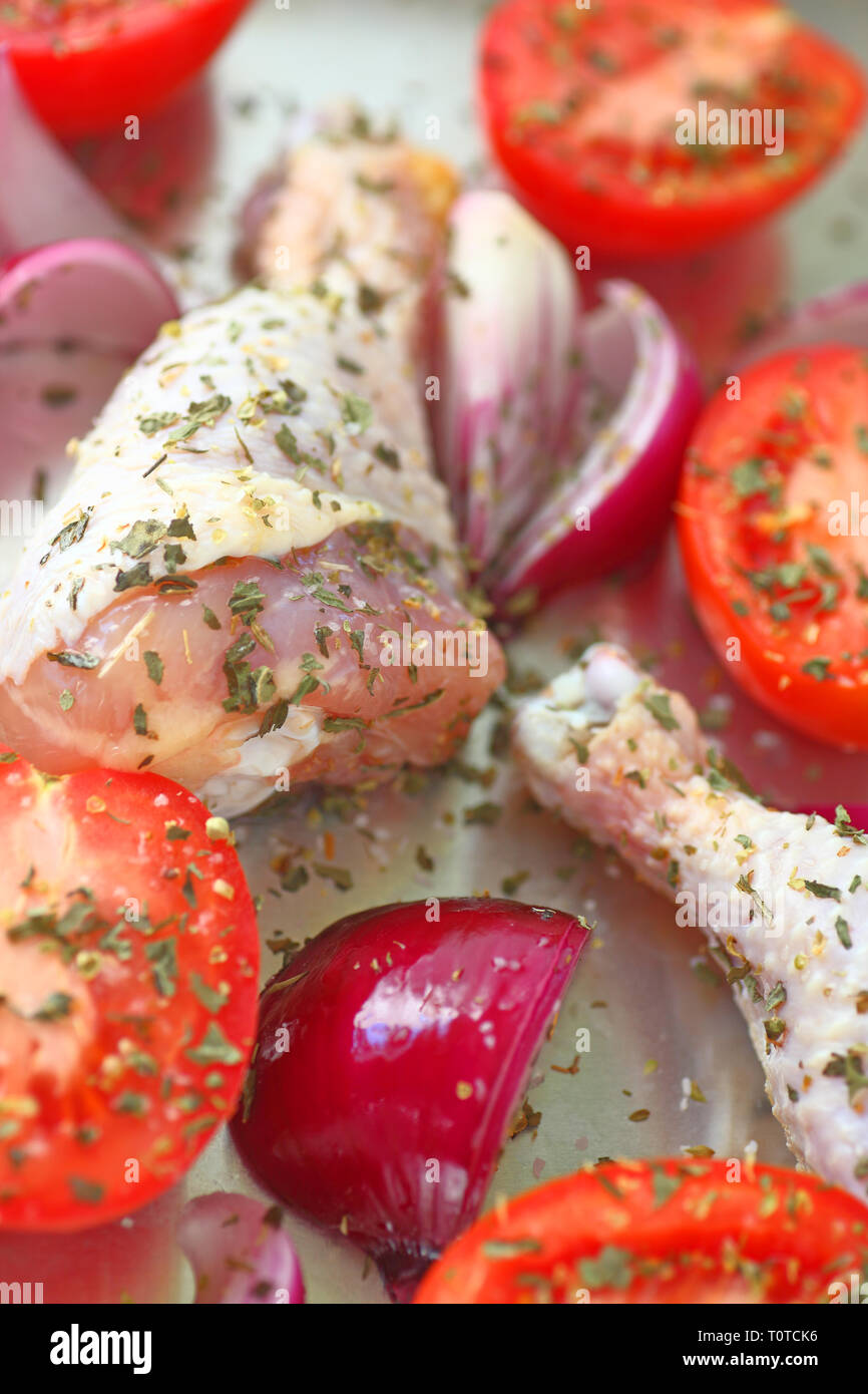 Vue verticale de poulet non cuit le dîner avec les tomates Roma et d'oignon rouge Banque D'Images