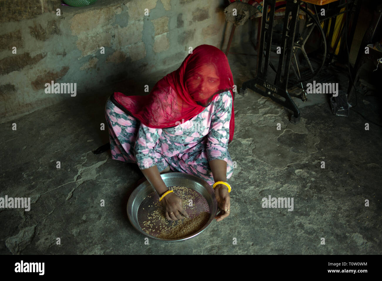 Une femme musulmane portant un voile prépare millet dans sa maison. Village de Kakani, Jodhpur, Rajasthan, Inde. Banque D'Images