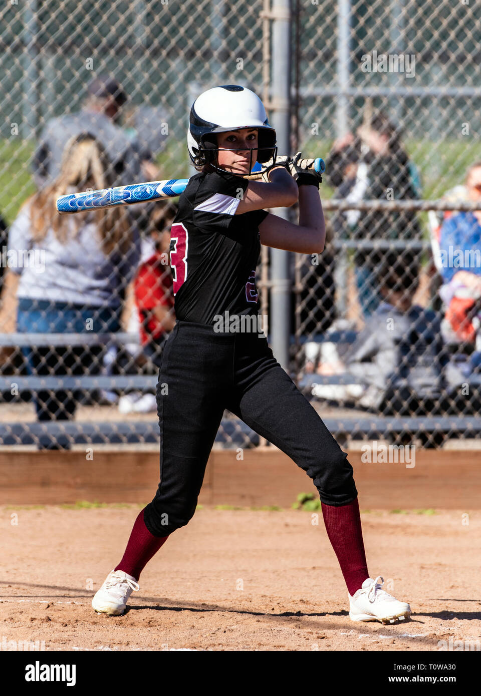 Joueur de softball féminin en uniforme noir suivi de la fuite de son tube en dehors du terrain au cours du jeu. Banque D'Images