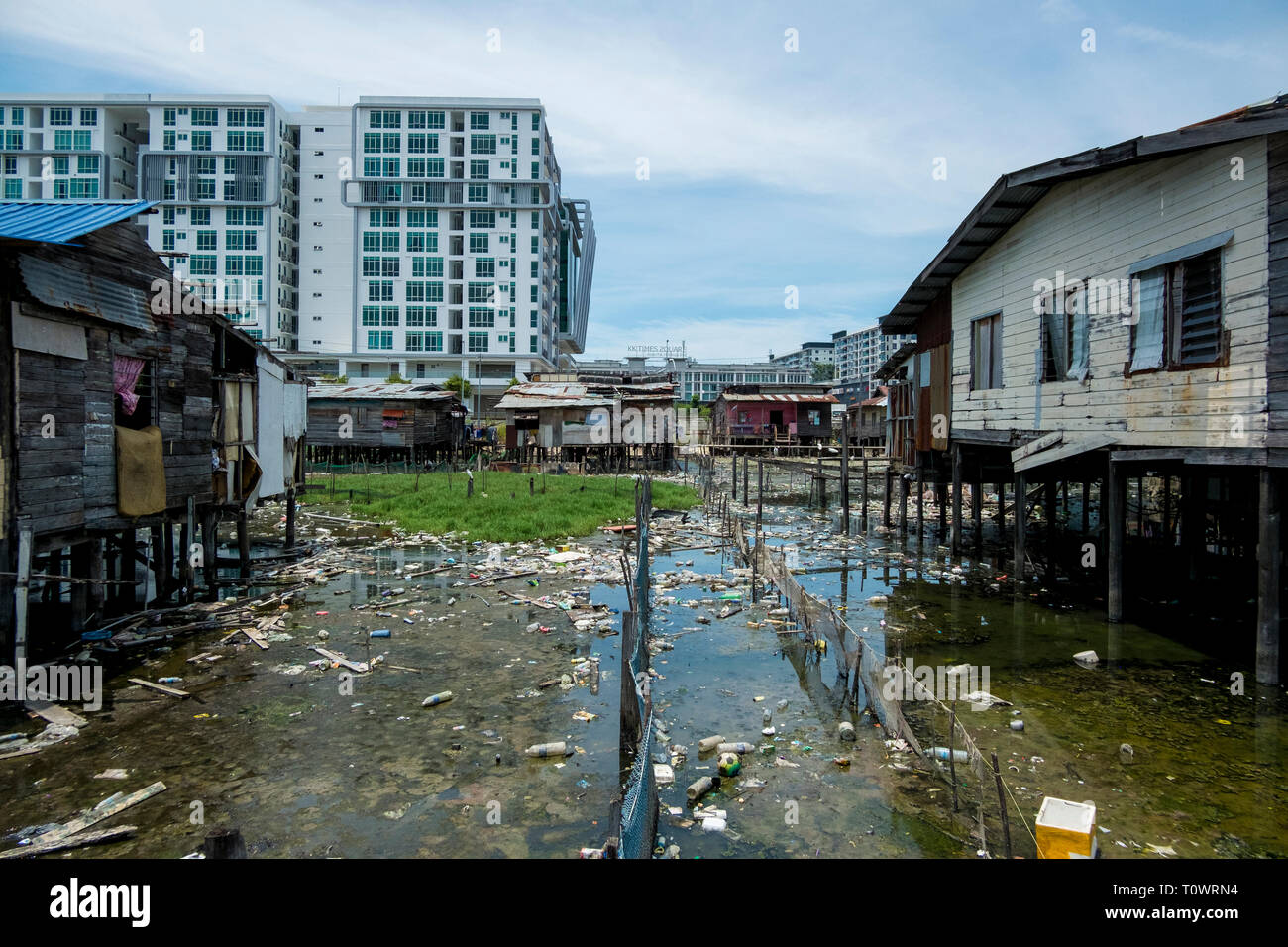 Une maison sur pilotis du village traditionnel de l'eau règlement se trouve en face du développement moderne à Kota Kinabalu, Sabah, Bornéo, Malaisie. Banque D'Images