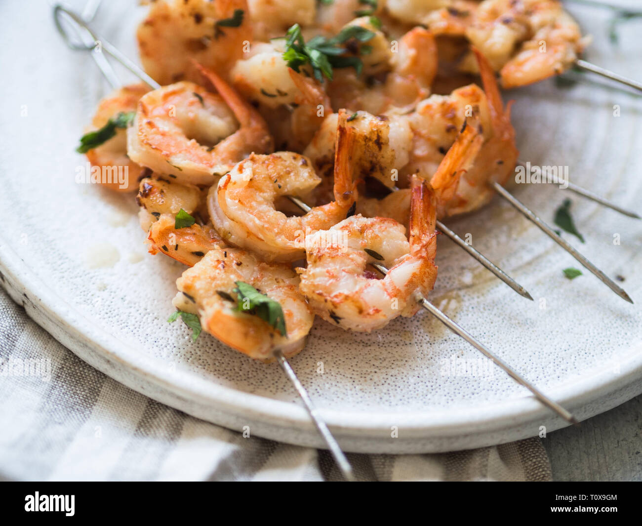 Crevettes épicées grillées sur des brochettes de métal avec le persil et le jus de lime on white plate Banque D'Images