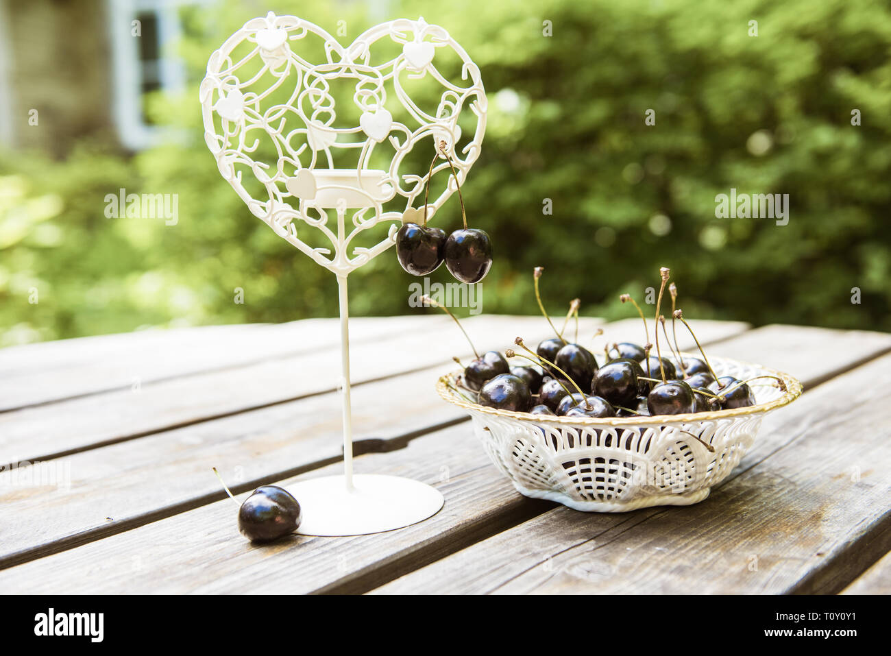 Cerises noires baies dans une assiette blanche sur la table en bois Banque D'Images