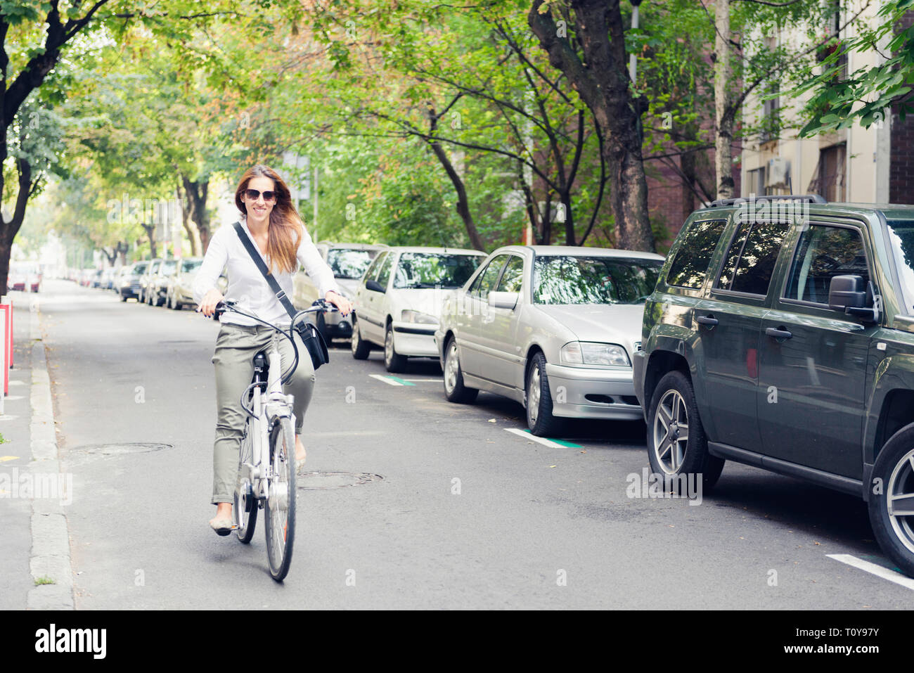 Équitation femme vélo électrique sur une rue de la ville Banque D'Images