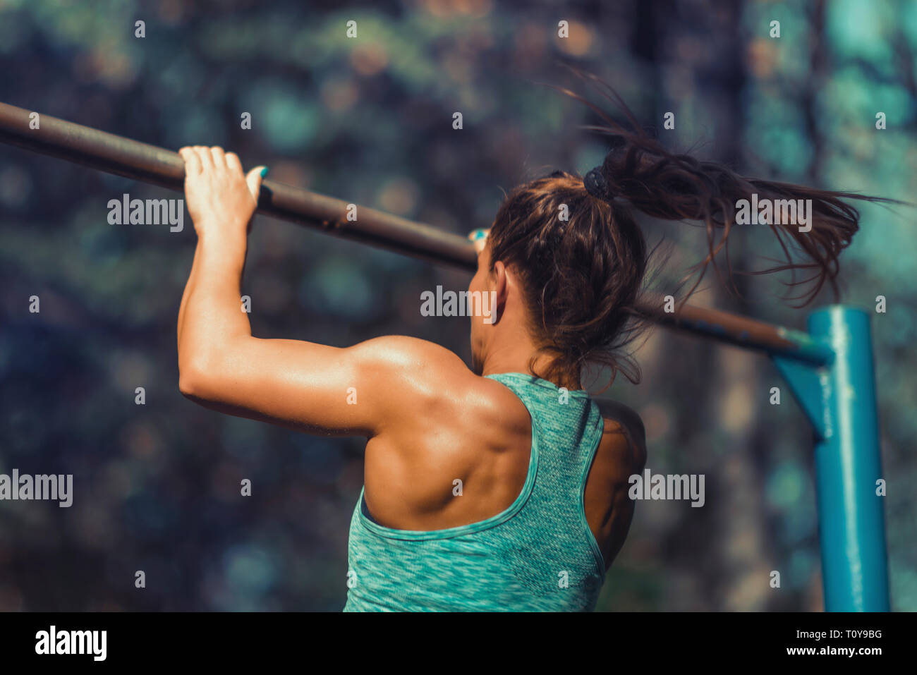 Woman exercising on barre horizontale à l'extérieur, dans un parc public. Banque D'Images