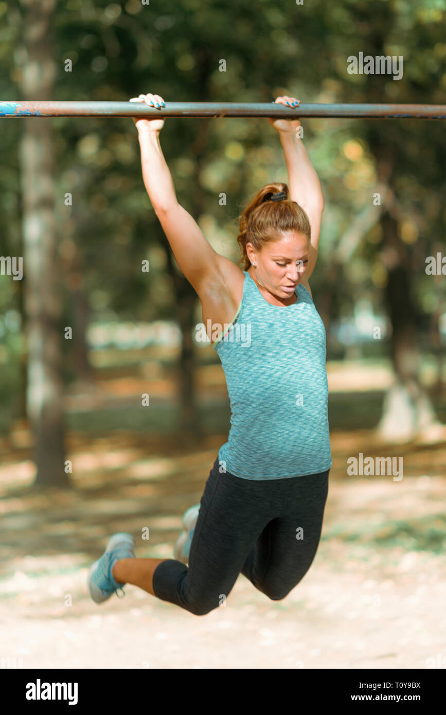 Woman exercising on barre horizontale à l'extérieur, dans un parc public. Banque D'Images