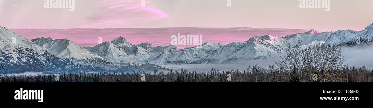 Panorama d'un coucher de soleil rose sur la chaîne de montagnes couvertes de neige près de la rivière Knik d'Alaska. Banque D'Images