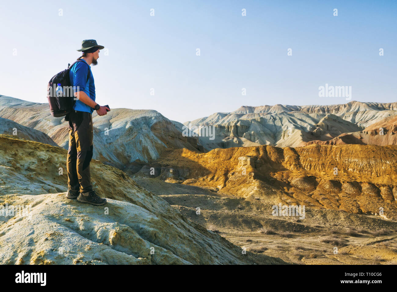 Traveler guy se tient sur le bord d'une colline dans l'arrière-plan d'un paysage de montagnes désertiques. Altyn-Emel National Park. Kazakhstan Banque D'Images