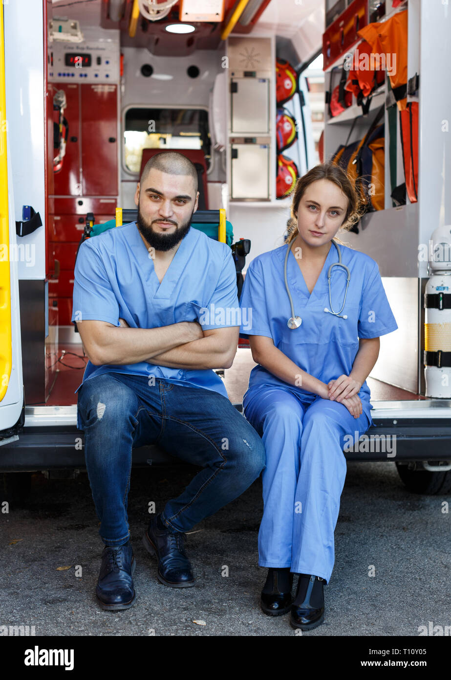 Portrait de deux ambulanciers positif assis en voiture ambulance Banque D'Images