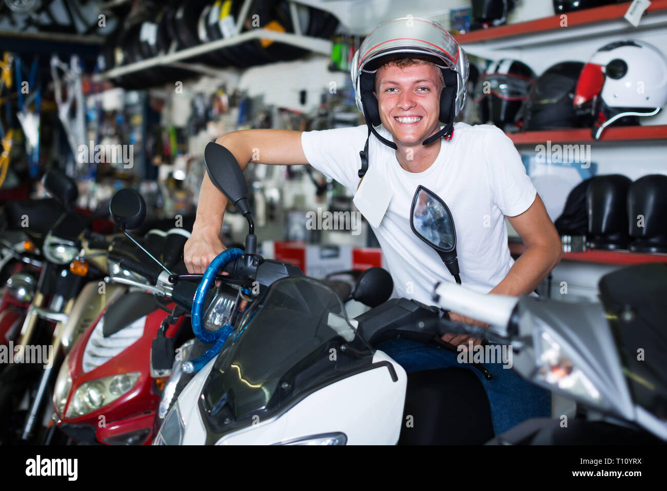 Homme 29 ans dans le casque est assis sur la moto dans la boutique. Banque D'Images