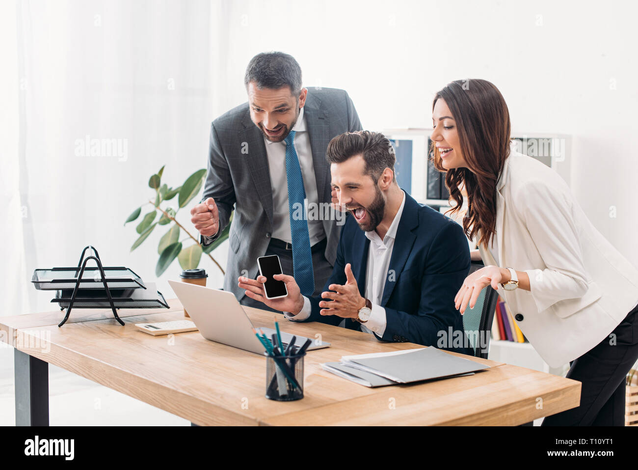 Collègues à table à la à l'ordinateur portable et de réjouissance dans office Banque D'Images