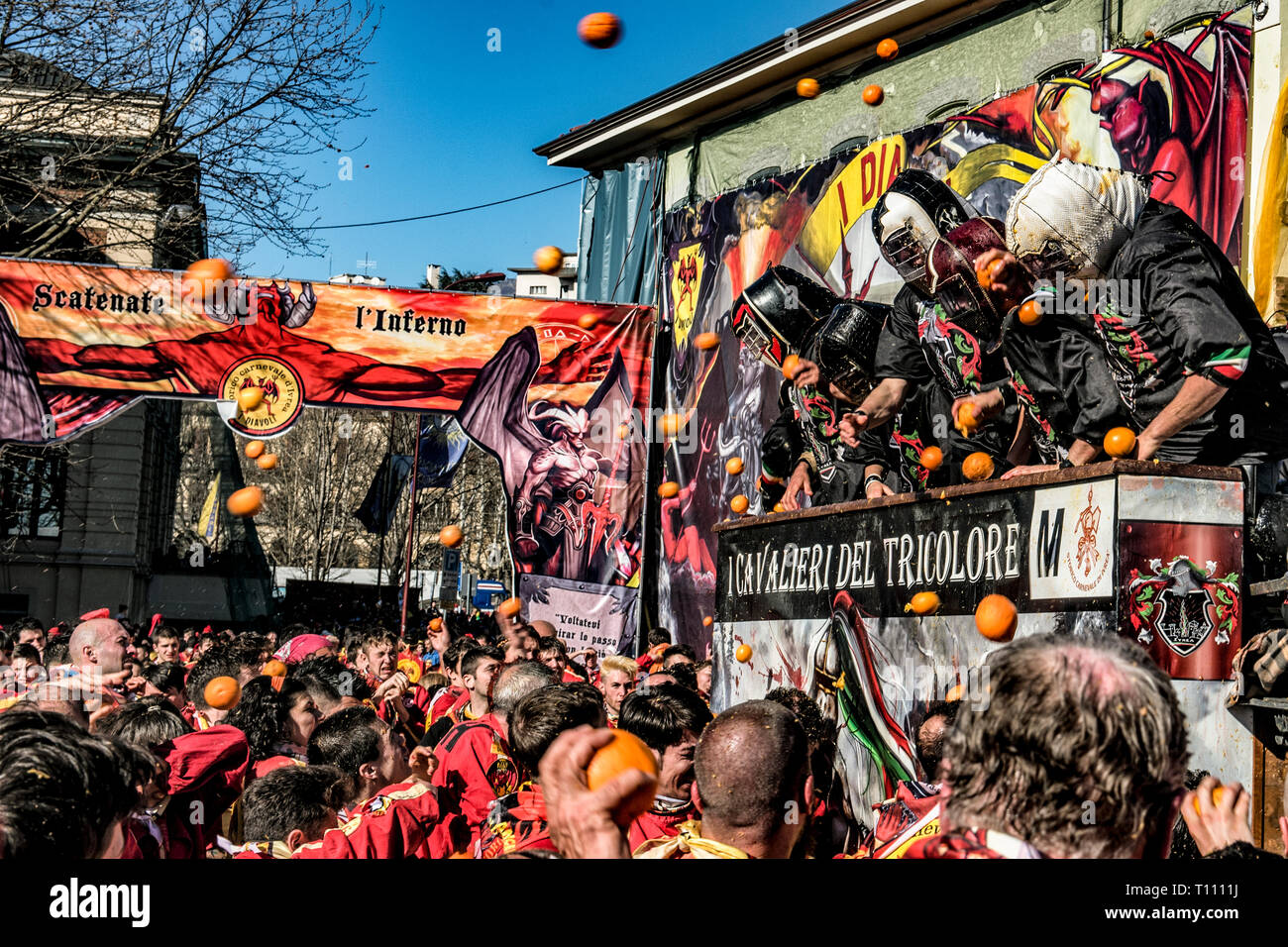 Faits saillants de la bataille de l'Orange, à Ivrea, près de Turin, en Italie, où les flammes orange sur le terrain l'attaque aux lanceurs d'orange qui defende eux-mêmes sur le chariot, et des courses d'orange Banque D'Images