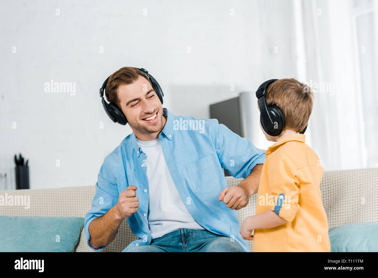 Heureux père fils d'âge préscolaire avec écoute au casque en musique à la maison Banque D'Images