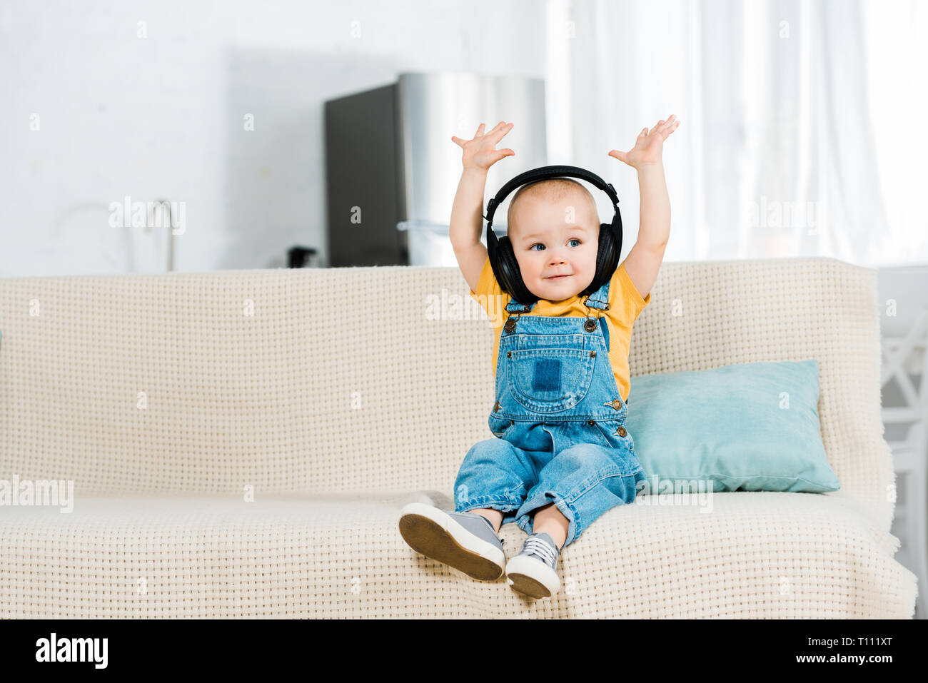 Adorable bébé de sexe masculin dans les écouteurs avec les mains dans l'air d'écouter la musique à la maison with copy space Banque D'Images