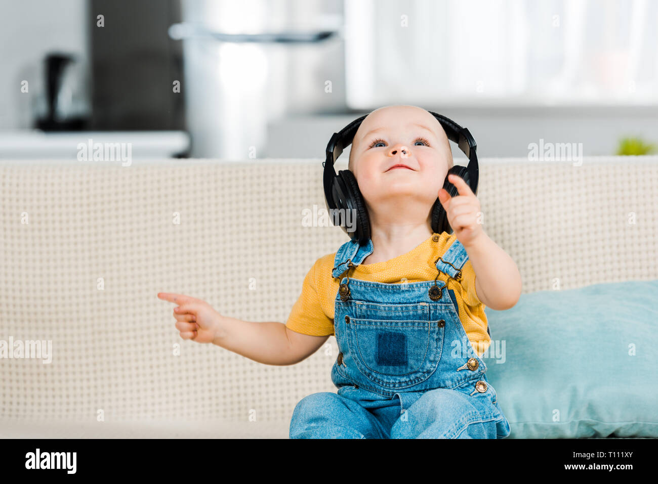 Adorable bébé de sexe masculin dans les écouteurs et l'écoute de musique à la maison Banque D'Images
