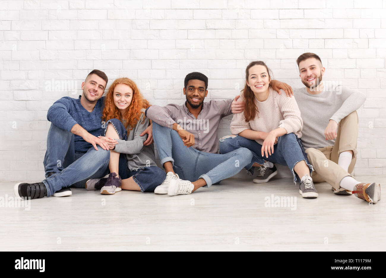 Diversité des étudiants assis sur le plancher et looking at camera Banque D'Images