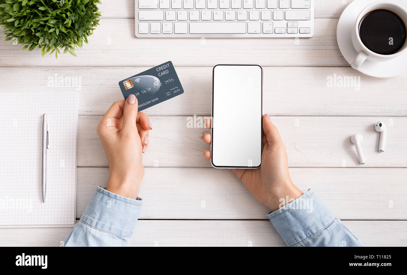 Femme à l'aide de carte de crédit et chèque en blanc smartphone, vue d'en haut Banque D'Images