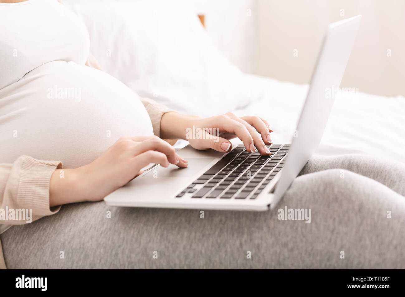 Femme enceinte baby blog lecture sur ordinateur portable Banque D'Images
