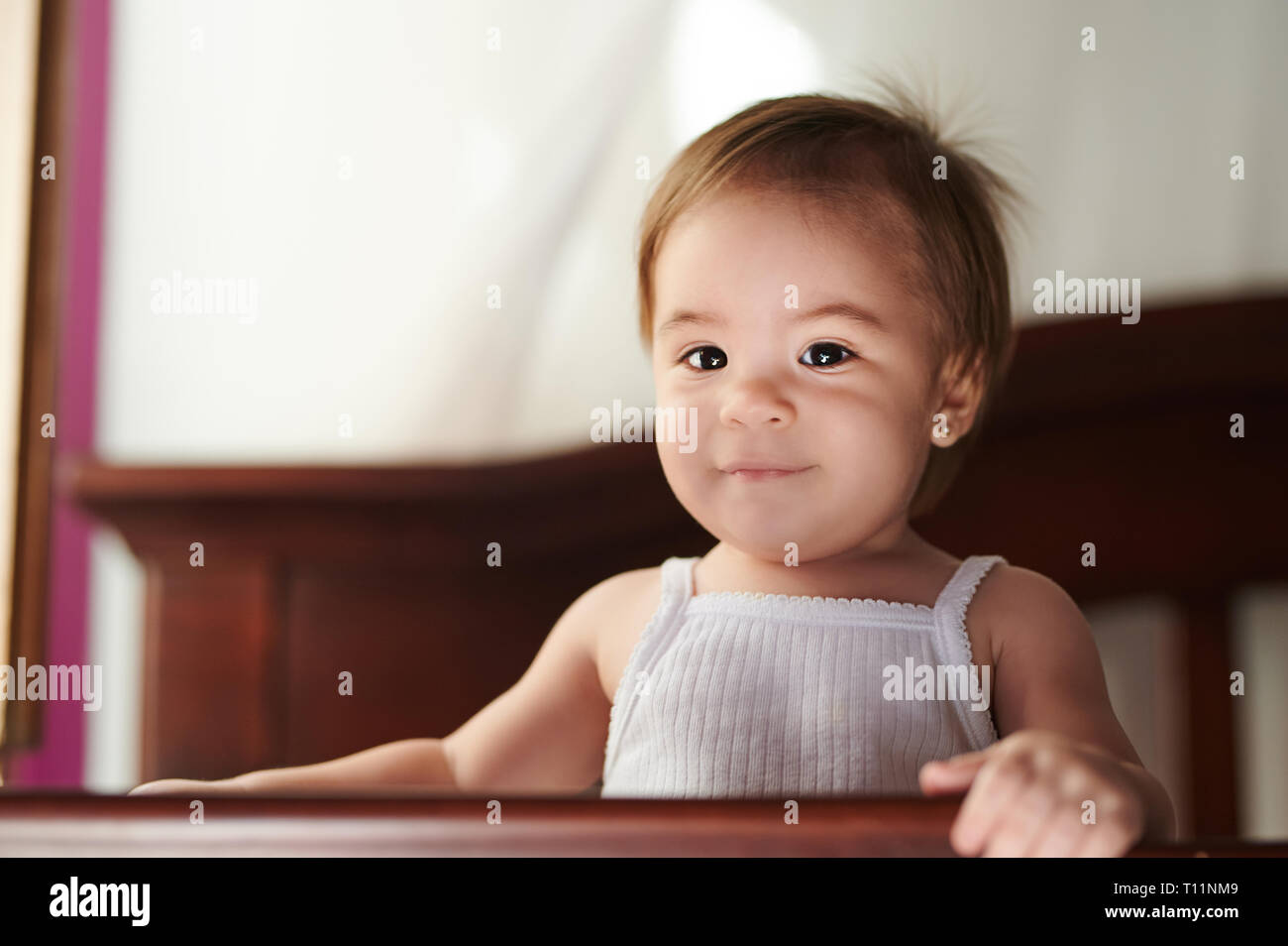 Portrait de bébé adorable Girl standing on lit-bébé Banque D'Images
