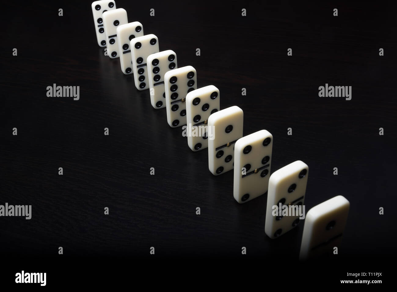 Dominos dans une rangée sur un fond noir Banque D'Images