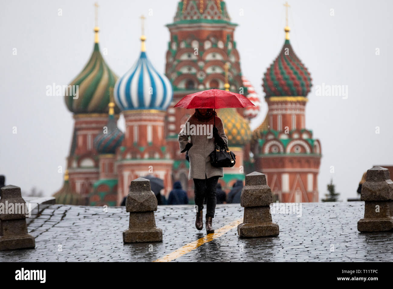 Temps de pluie à Moscou. Une fille avec un parapluie rouge sur la place rouge sur l'arrière-plan de la cathédrale Saint-Basile, dans le centre de Moscou, Russie Banque D'Images