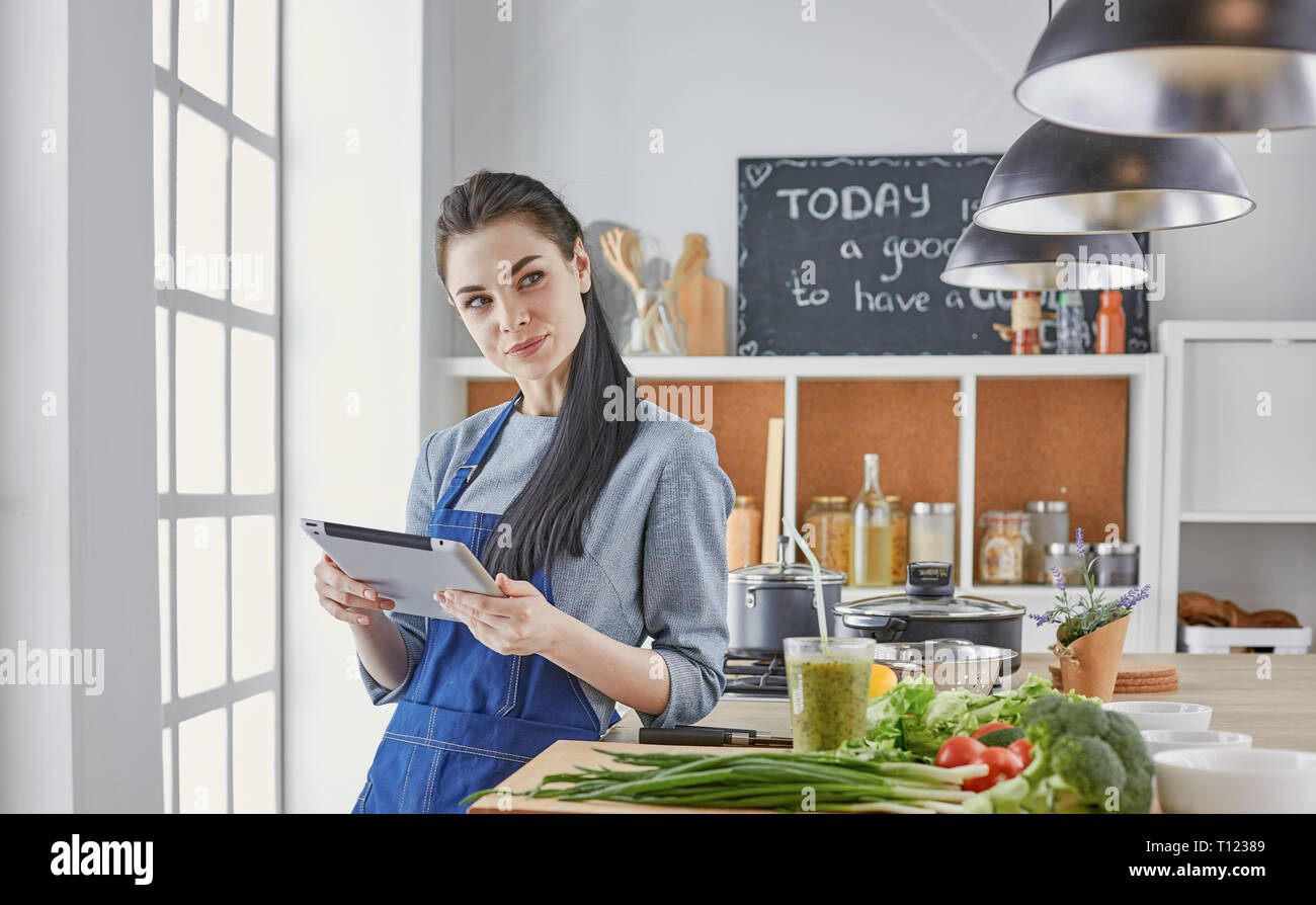 Femme heureuse à la tablette lecture cuisine cuisine recette Banque D'Images