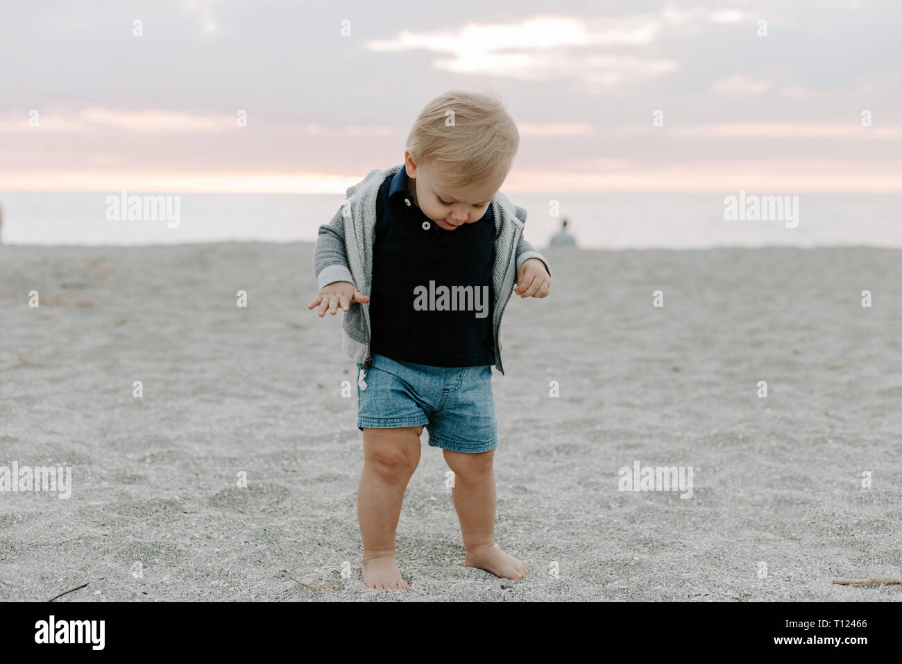 Portrait de Mignon petit bébé garçon enfant jouer et explorer dans le sable  à la plage pendant le coucher du soleil à l'extérieur en vacances in Hoodie  Sweat-shirt fermeture Éclair Photo Stock -