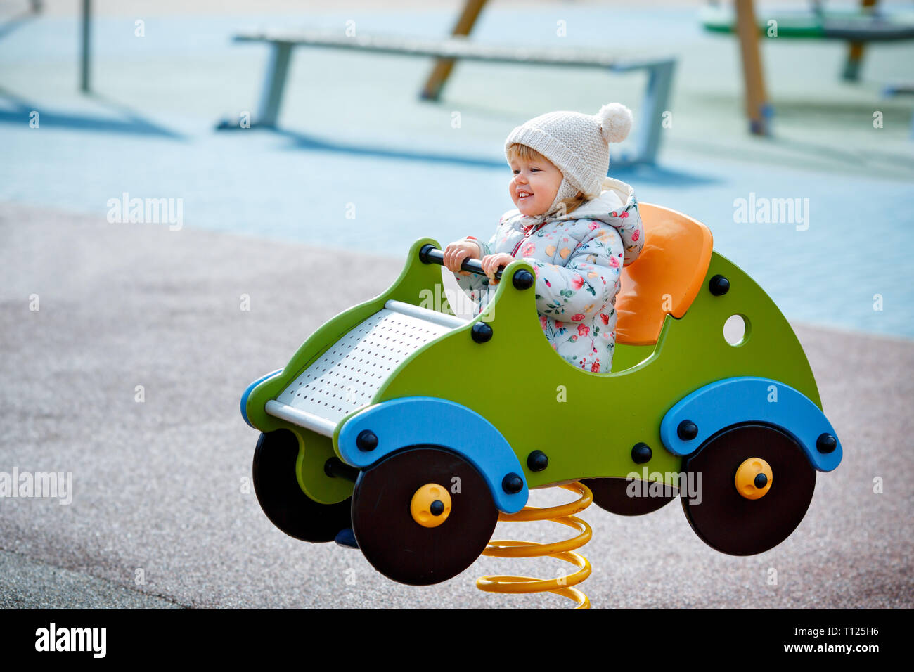 Adorable bébé fille assise dans une voiture sur l'aire de jeux