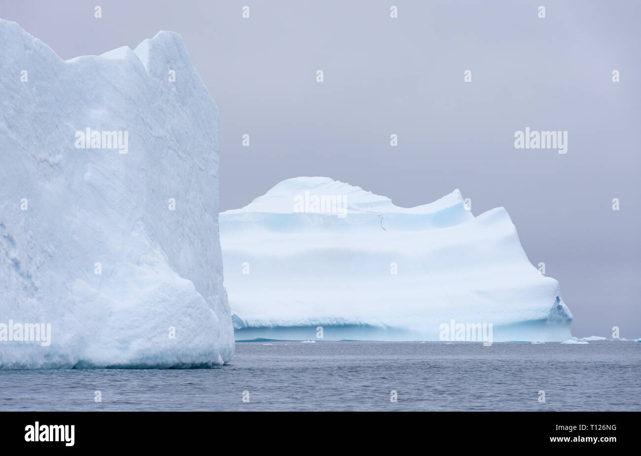 Deux grands icebergs flottant dans l'océan du sud de l'Antarctique avec un ciel couvert ci-dessus. Banque D'Images