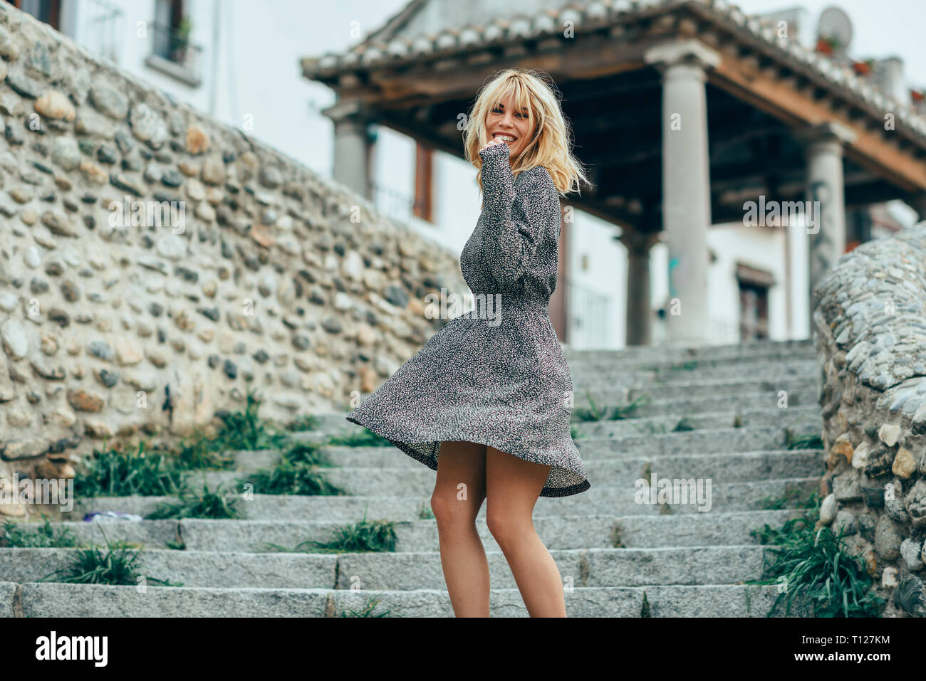 Smiling blonde girl wearing dress dancing en plein air. Banque D'Images