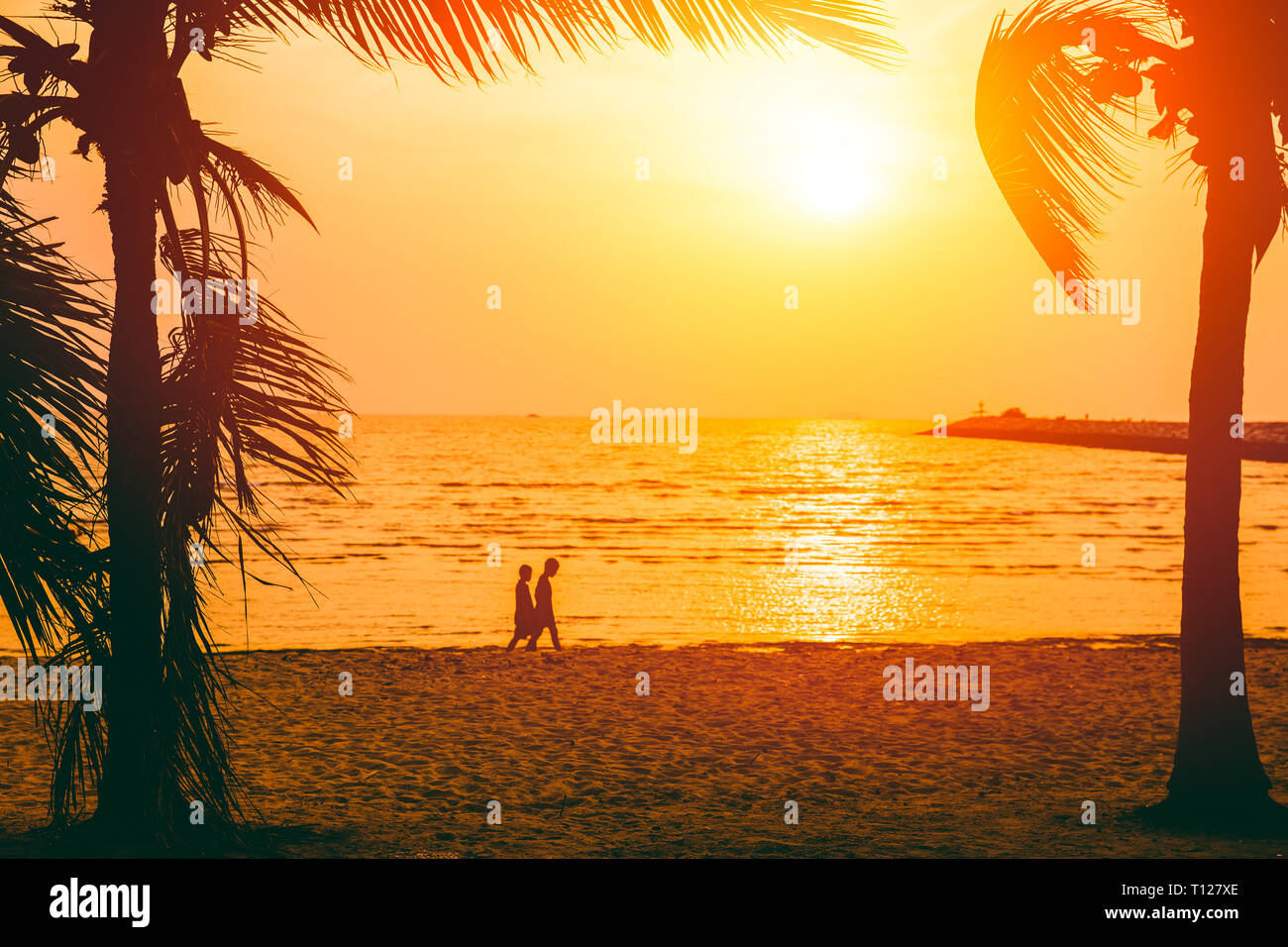 Silhouette de deux enfants marche à été mer plage coucher du soleil. Banque D'Images