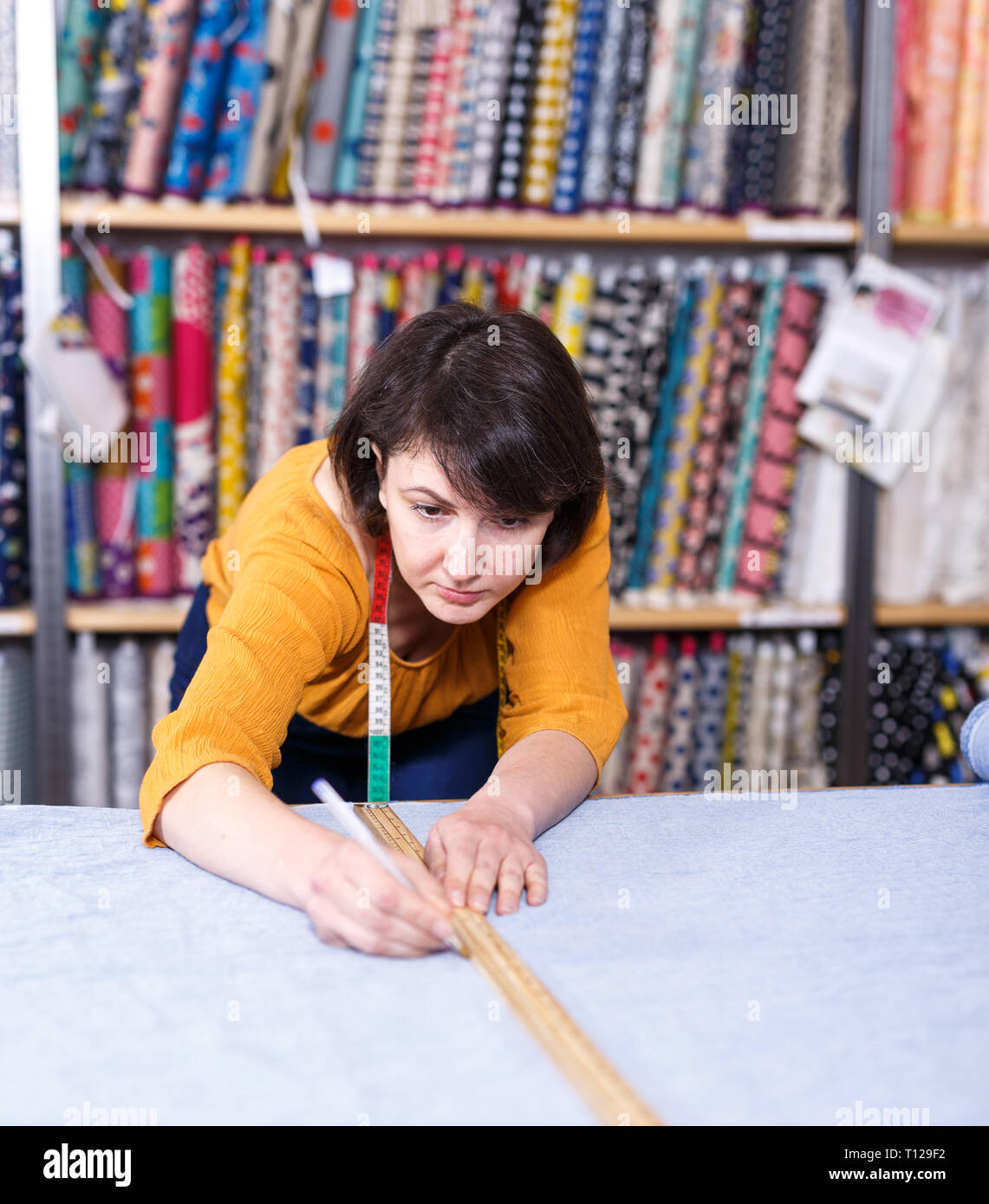 Vendeur de tissu femelle shop mesure et coupe off morceau de textile pour la couture Banque D'Images