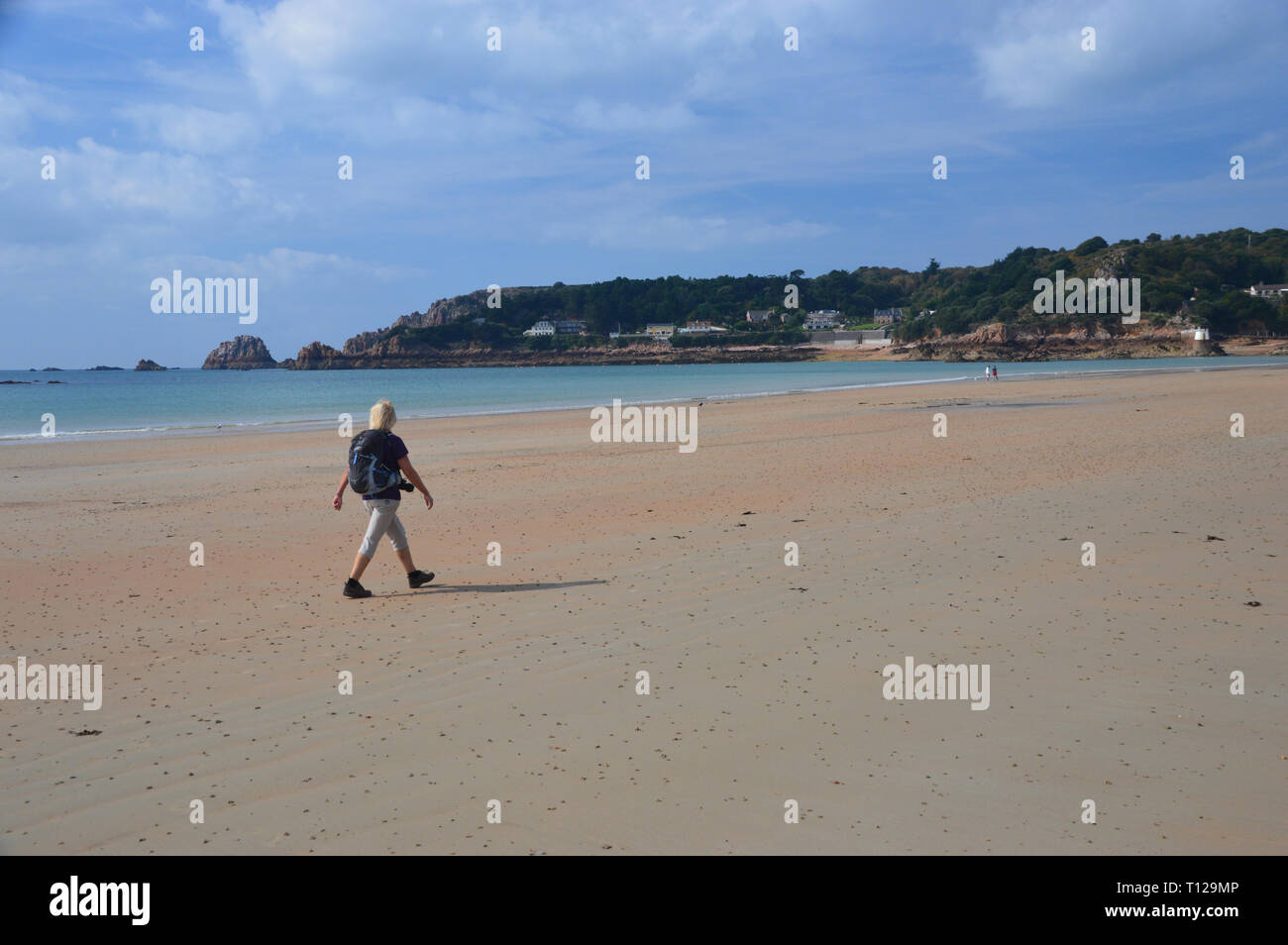Femme seule randonneur autour de la tour Martello rouge et blanc sur la plage de Saint Brélade Bay sur l'île de Jersey, Îles britanniques, Royaume-Uni. Banque D'Images